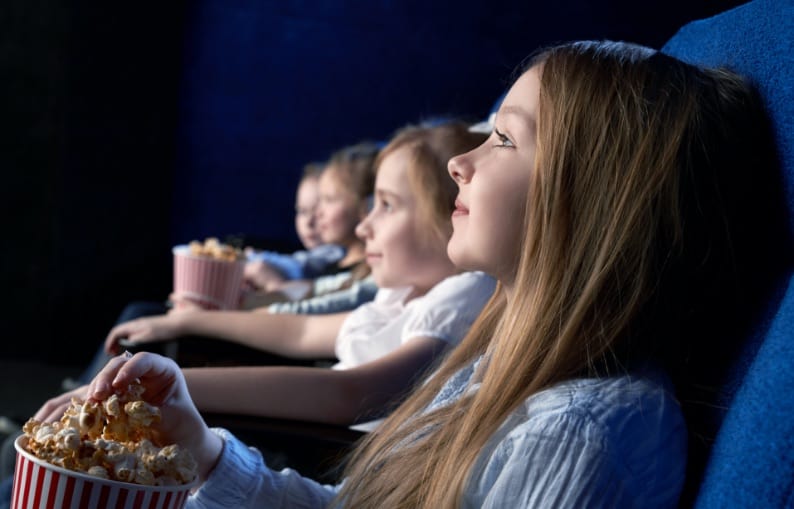Four kids watching a movie at the cinema